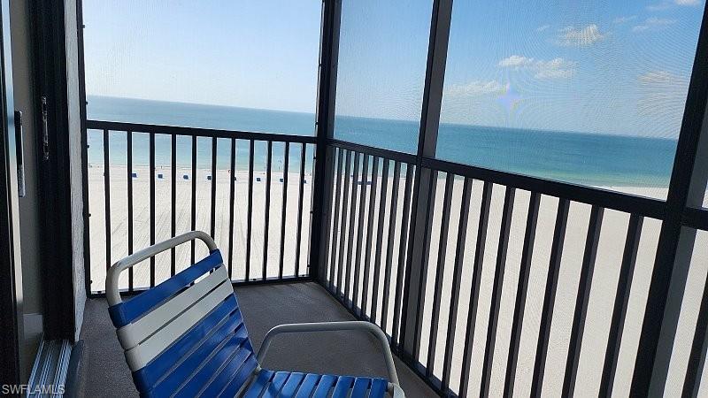 Balcony with a sunroom and view of water and beach