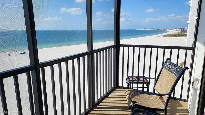 Private direct beachfront corner/end unit balcony showcasing sweeping Gulf views of Fort Myers Beach to Sanibel, the perfect setting for morning coffee or sunset relaxation. Comfortable chairs invite you to unwind while enjoying the sights and sounds of the gulf beach.