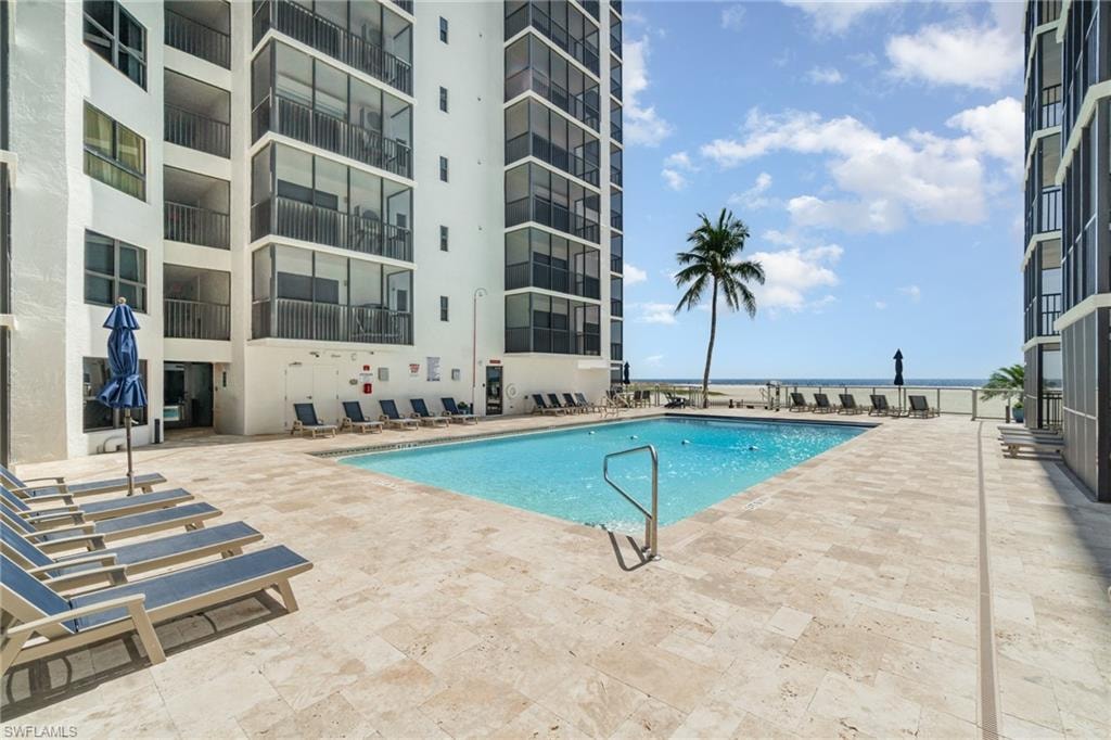 Resort-style beachfront pool framed by elegant coastal towers, offering expansive sun-drenched decking, lounge seating, and direct views of the sparkling Gulf beyond—an exceptional setting for refined seaside living.