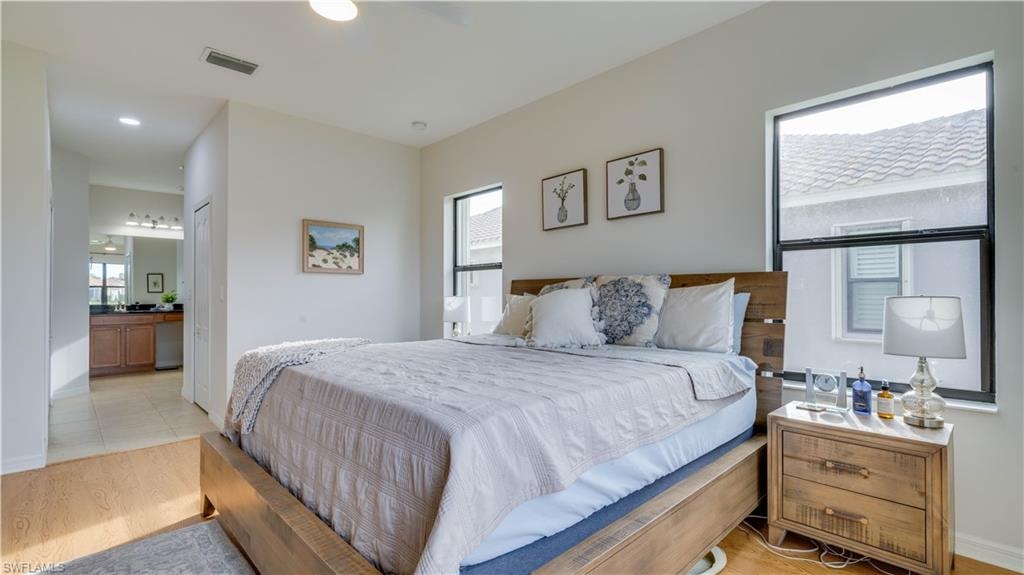 Bedroom featuring light wood-type flooring, a ceiling fan, and ensuite bathroom