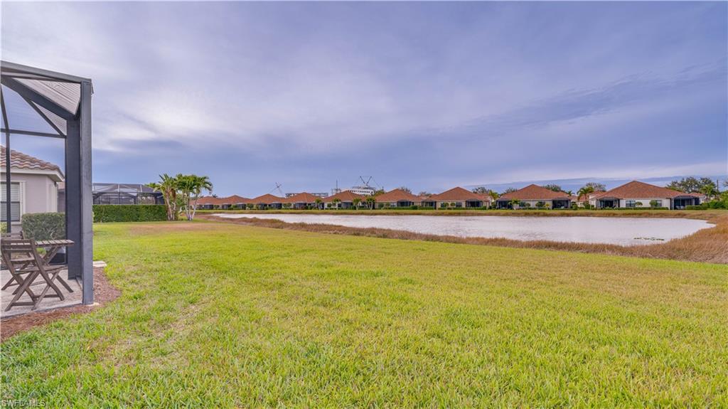 View of green lawn with a water view, a residential view, and glass enclosure