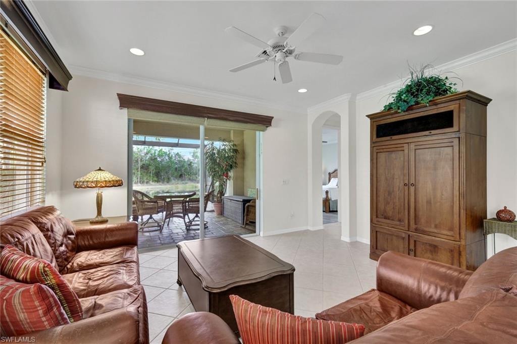 Living room with a ceiling fan, crown molding, arched walkways, light tile patterned floors, and recessed lighting
