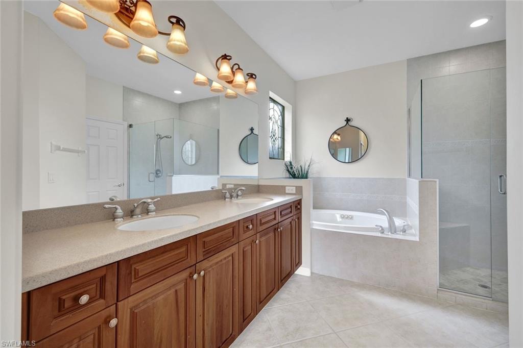 Bathroom featuring a shower stall, double vanity, a garden tub, light tile patterned floors, and recessed lighting