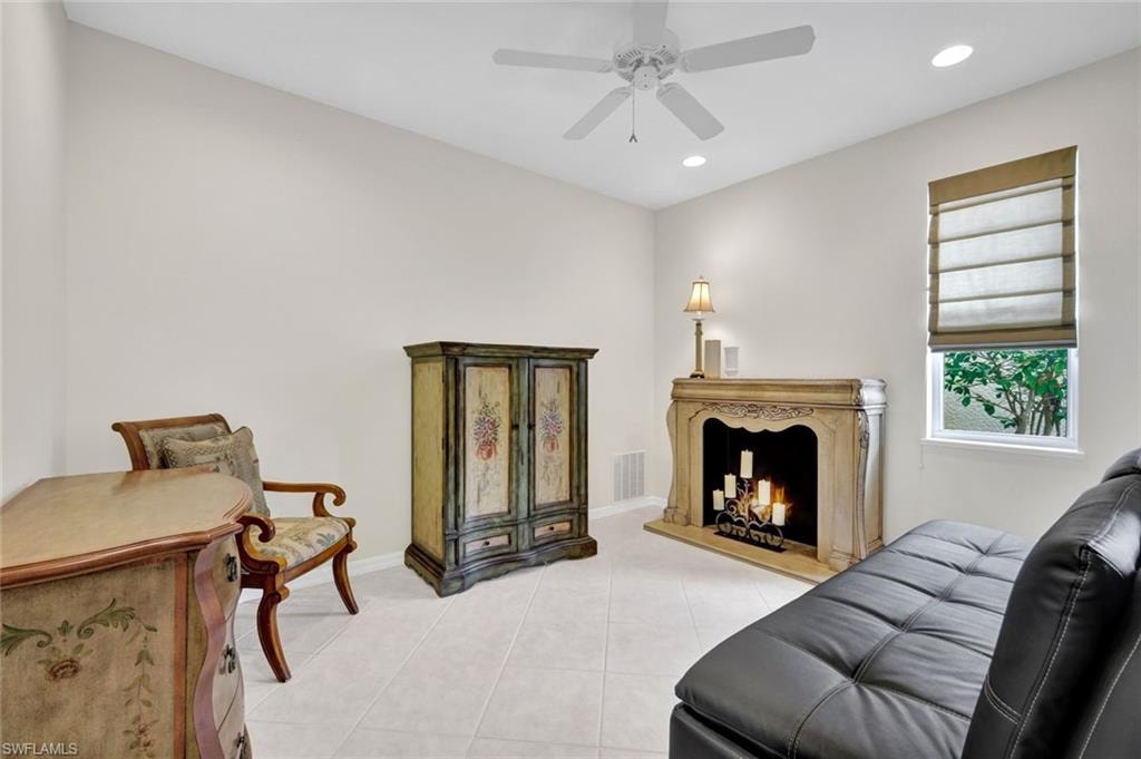 Living room featuring recessed lighting, light tile patterned floors, a lit fireplace, and a ceiling fan