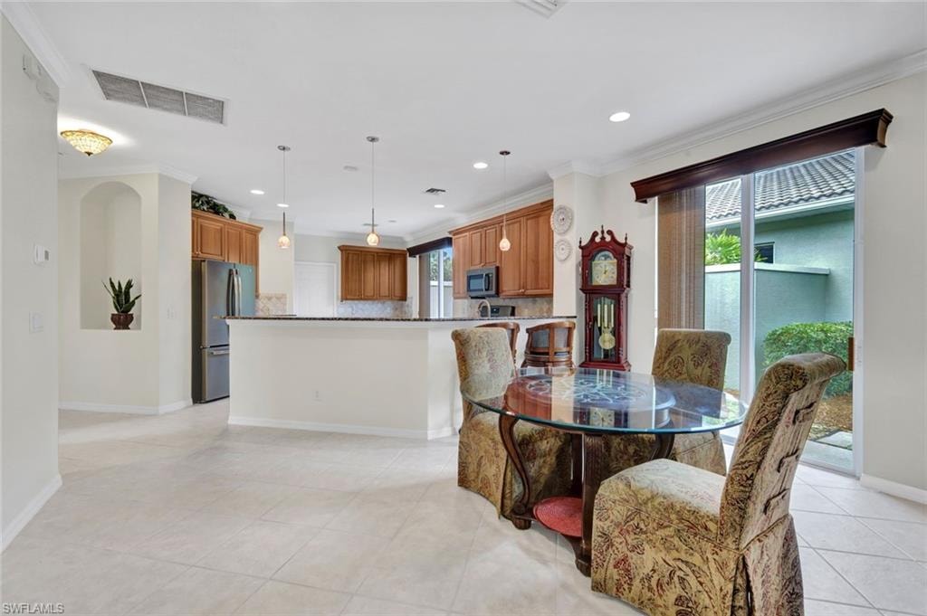 Dining area with crown molding, light tile patterned floors, and recessed lighting