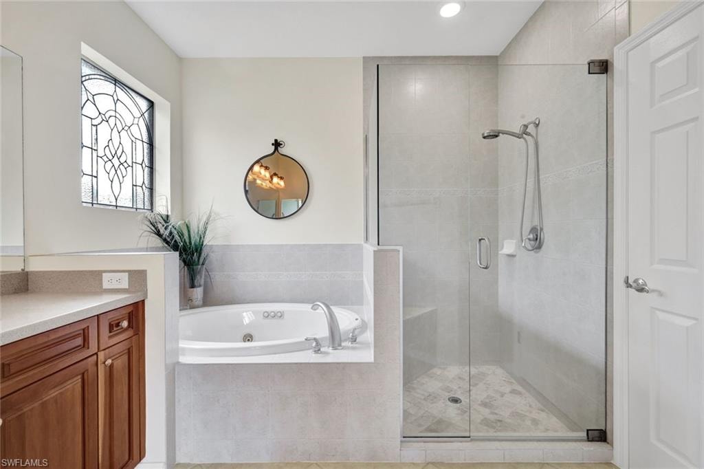 Bathroom with a shower stall, vanity, a whirlpool tub, and recessed lighting
