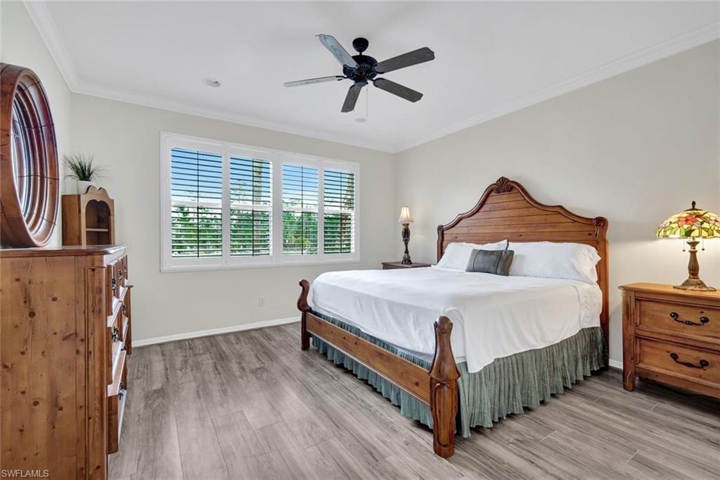 Bedroom featuring light wood-style flooring, crown molding, and ceiling fan