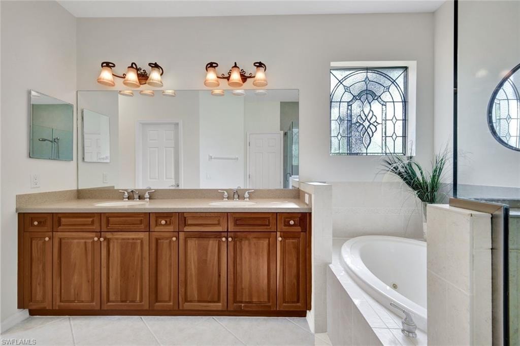 Full bathroom with double vanity, a jetted tub, and light tile patterned floors