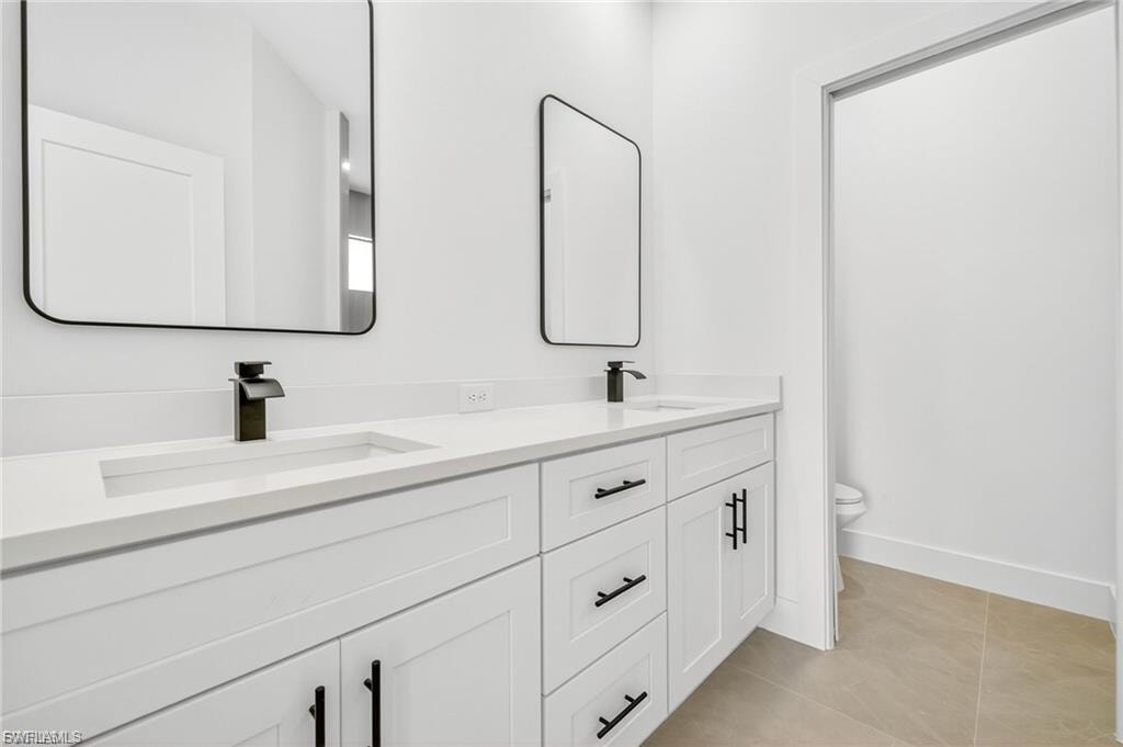 Full bath with double vanity and light tile patterned flooring
