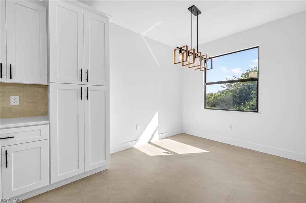 Unfurnished dining area featuring hanging lights and concrete flooring