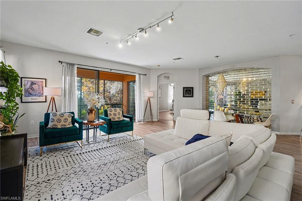 Living room featuring arched walkways, light wood finished floors, and rail lighting