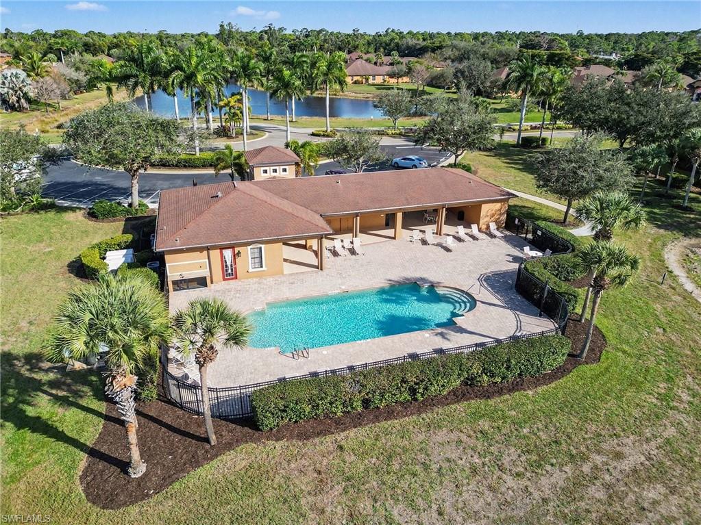 Community pool featuring a patio, a fenced backyard, a water view, and view of scattered trees