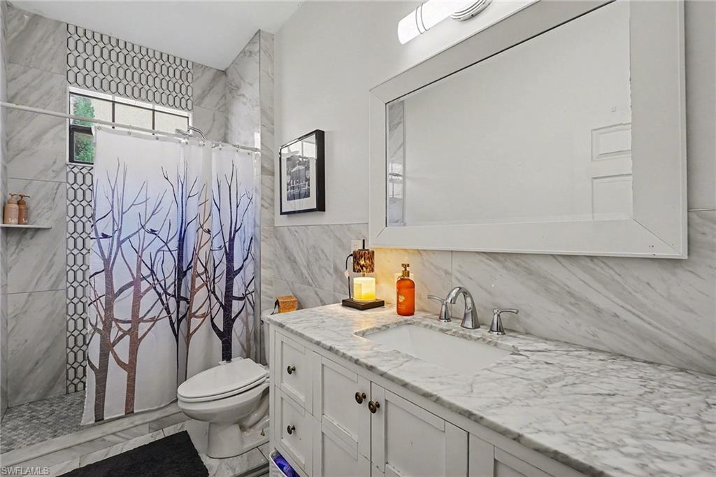 Main Bathroom with a tile shower, vanity, and tile walls
