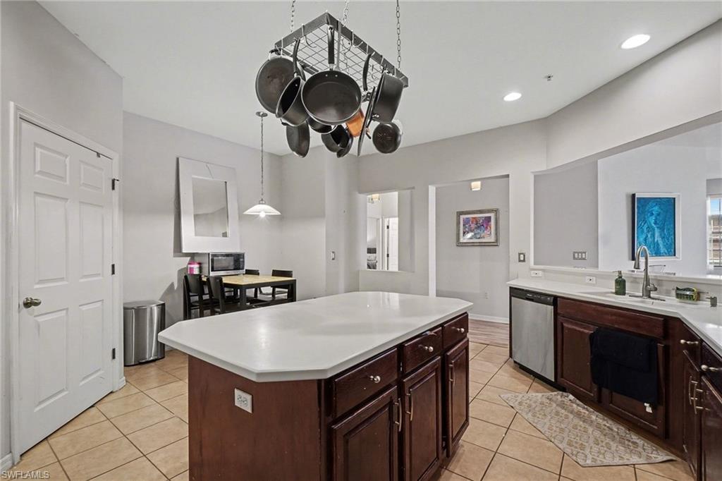 Kitchen featuring light countertops, light tile patterned floors, stainless steel appliances, a kitchen island, and pendant lighting