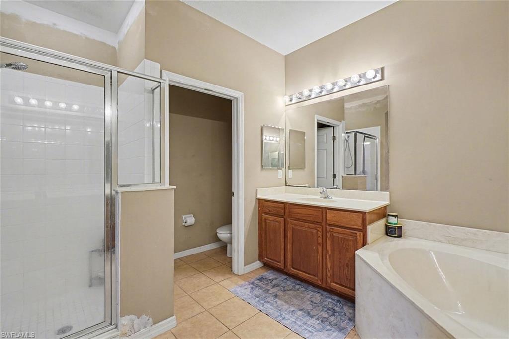 Primary Bathroom featuring a stall shower, vanity, light tile patterned flooring, and a garden tub