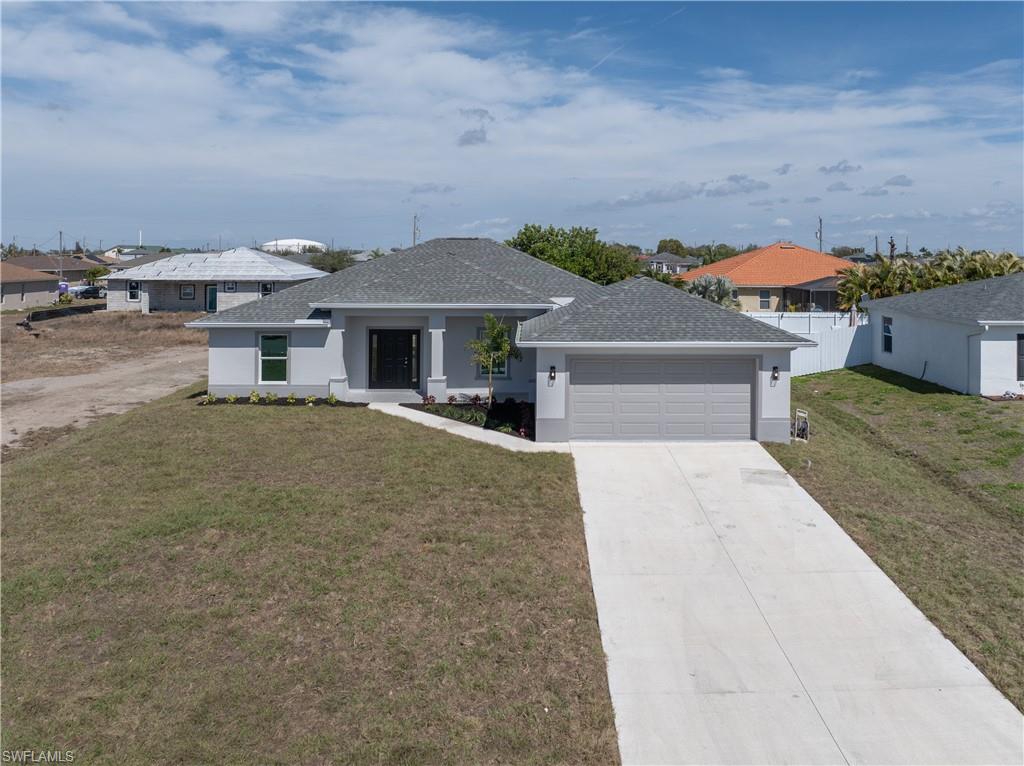 View of front of property featuring a front lawn, a shingled roof, driveway, and stucco siding