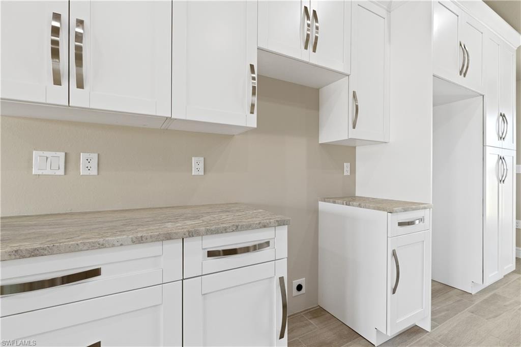 Kitchen with white cabinetry, light stone countertops, and wood tiled floors
