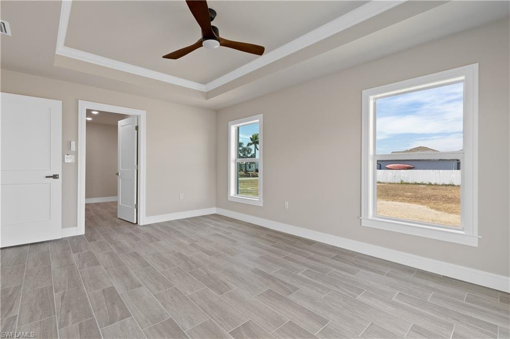 Unfurnished bedroom with a ceiling fan, crown molding, wood tiled floors, and a raised ceiling