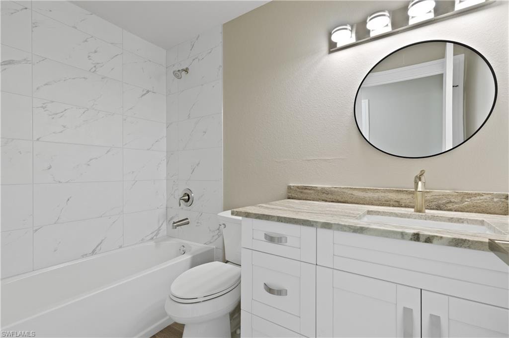 Full bathroom with vanity, bathtub / shower combination, and a textured wall