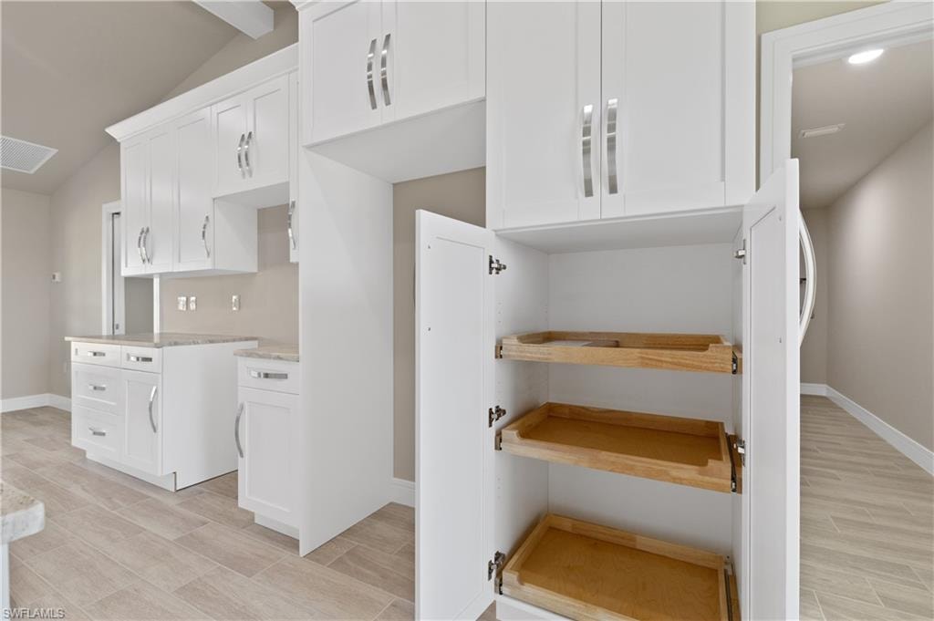 Kitchen featuring white cabinets, wood finish floors, and lofted ceiling