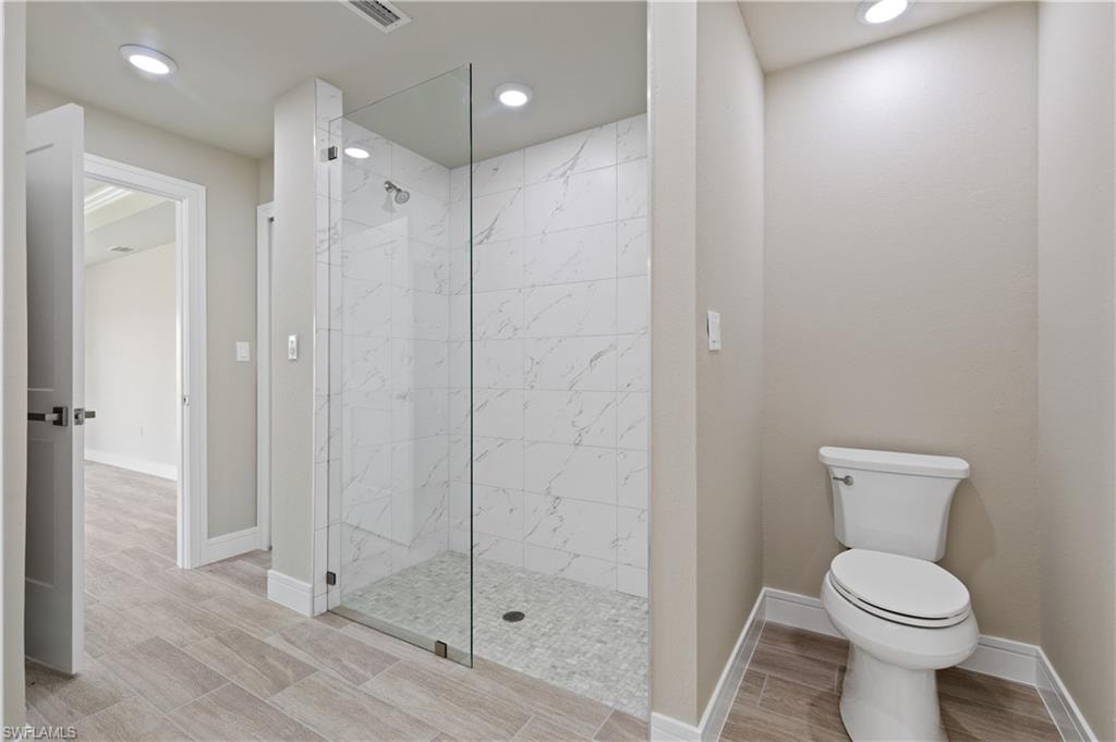 Bathroom featuring a marble finish shower, wood finish floors, and recessed lighting