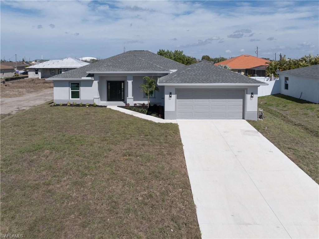 View of front of property featuring a front yard, concrete driveway, stucco siding, a garage, and a shingled roof
