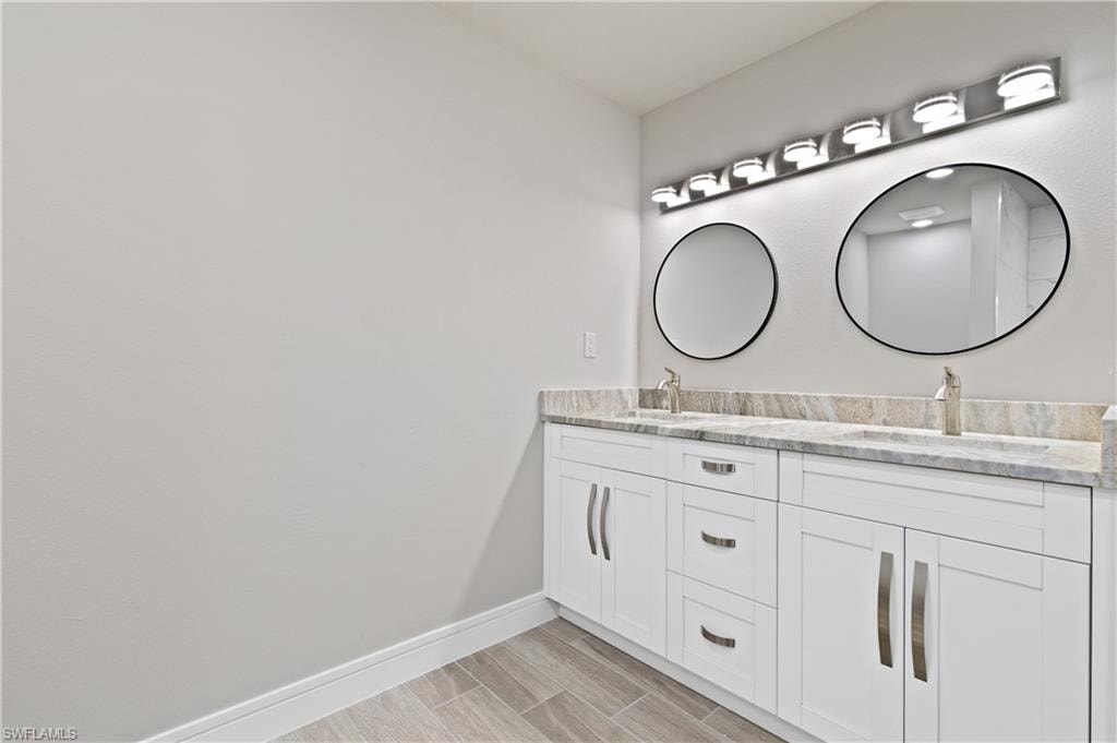 Full bath with double vanity and wood finish floors