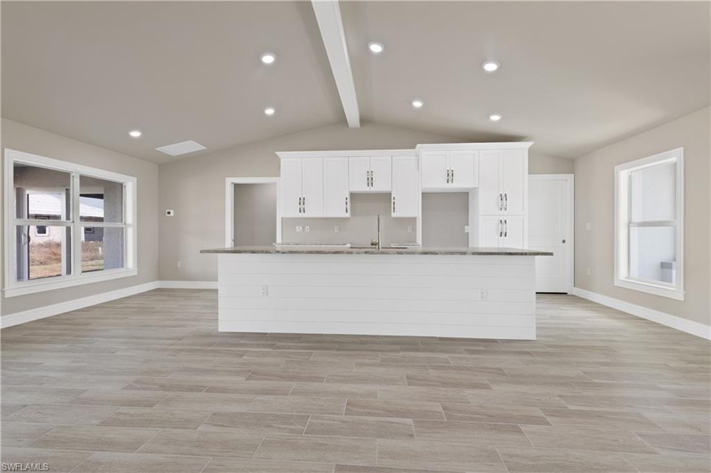 Kitchen with plenty of natural light, white cabinetry, wood finish floors, recessed lighting, and beamed ceiling