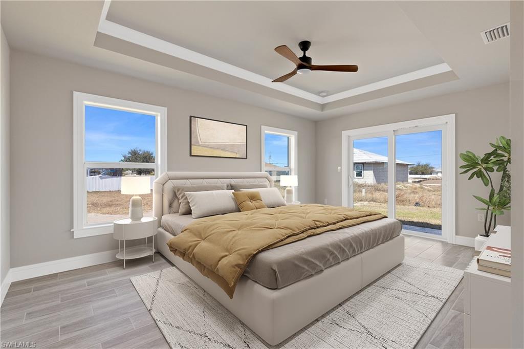 Bedroom featuring wood tiled floors, access to exterior, a ceiling fan, and a tray ceiling