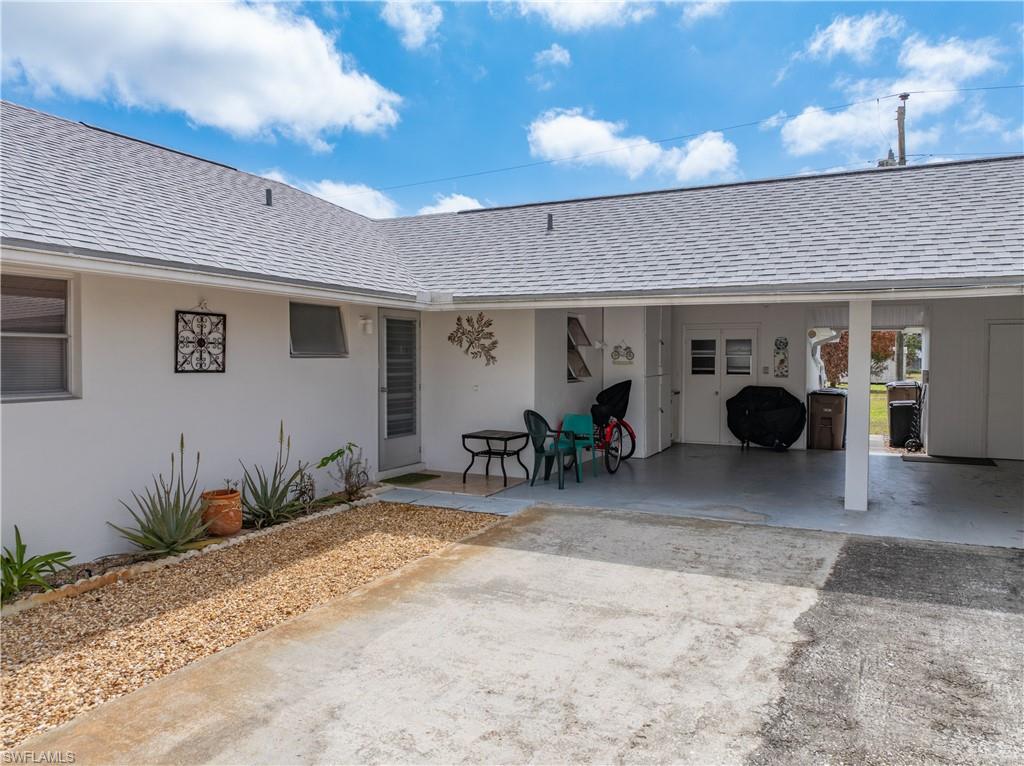Entrance to property with roof with shingles, stucco siding, and a patio area