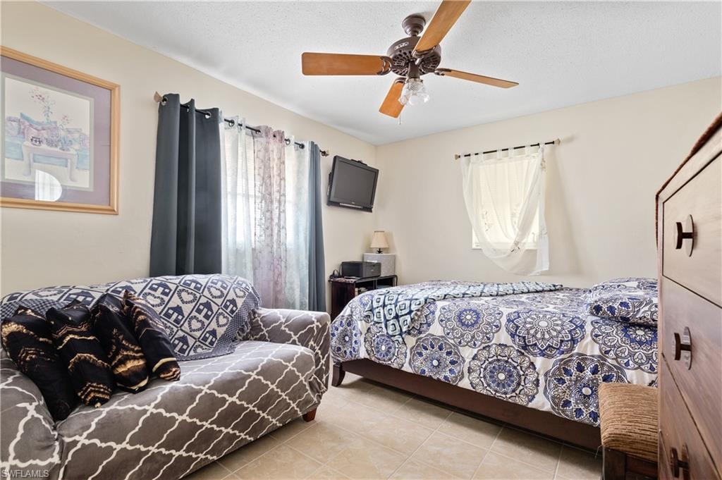 Bedroom with light tile patterned floors, a ceiling fan, and a textured ceiling