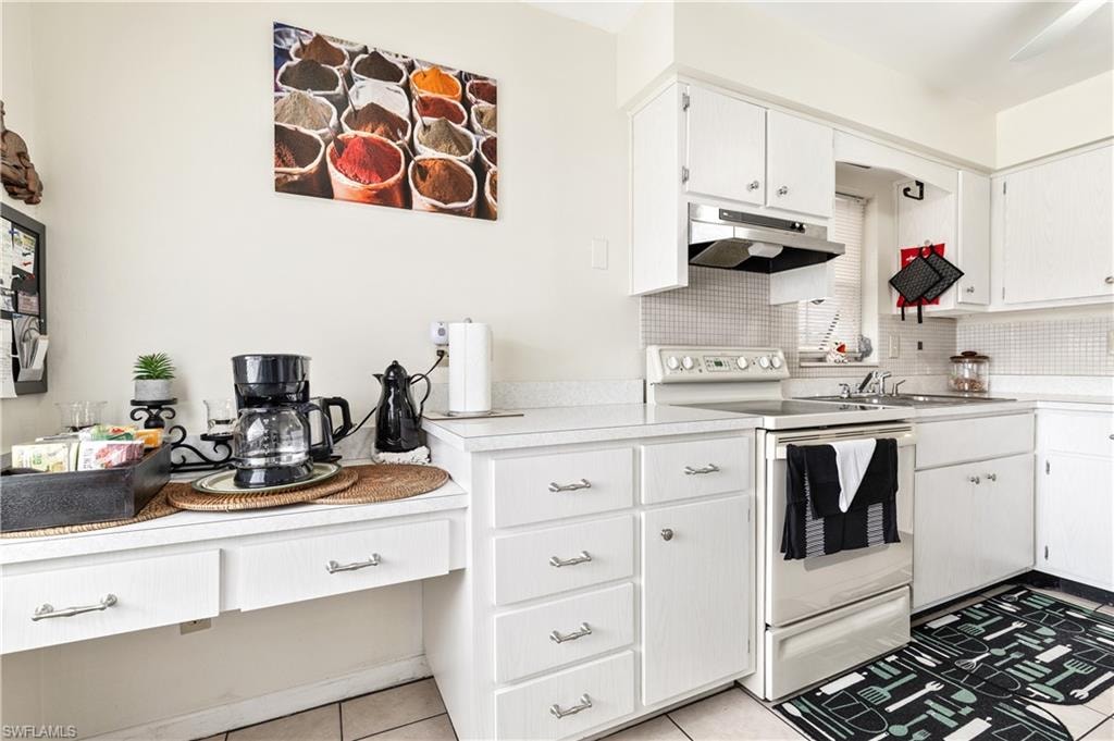 Kitchen with white electric range oven, light countertops, white cabinetry, and decorative backsplash