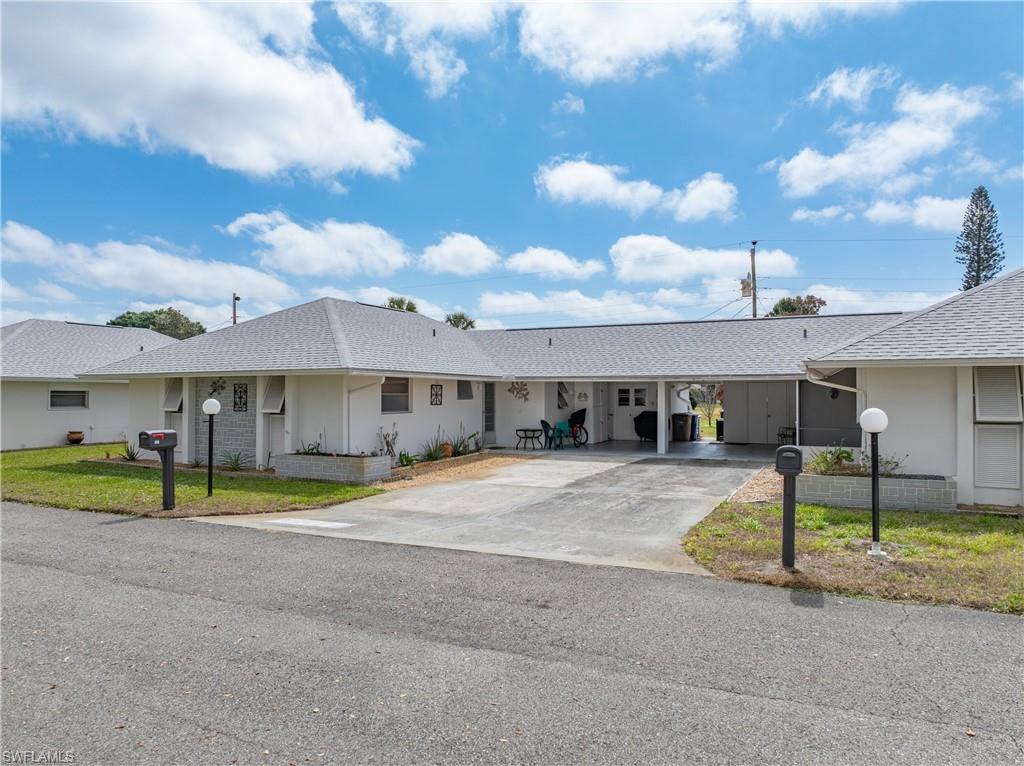 View of front of property with roof with shingles, a carport, concrete driveway, and a front yard