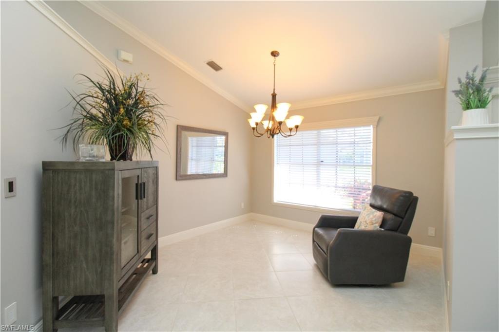 Living area with lofted ceiling, a notable chandelier, visible vents, and ornamental molding
