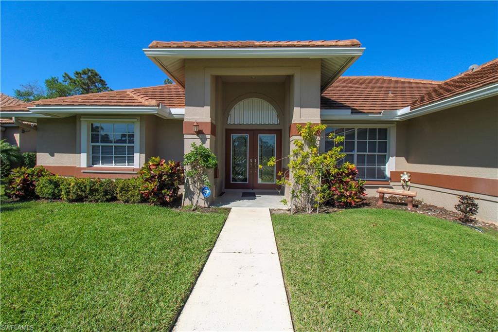 Doorway to property with french doors, a lawn, and stucco siding