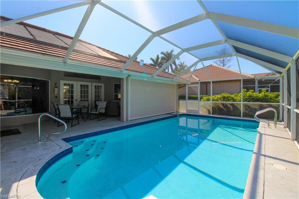 Pool featuring glass enclosure, a patio area, and french doors