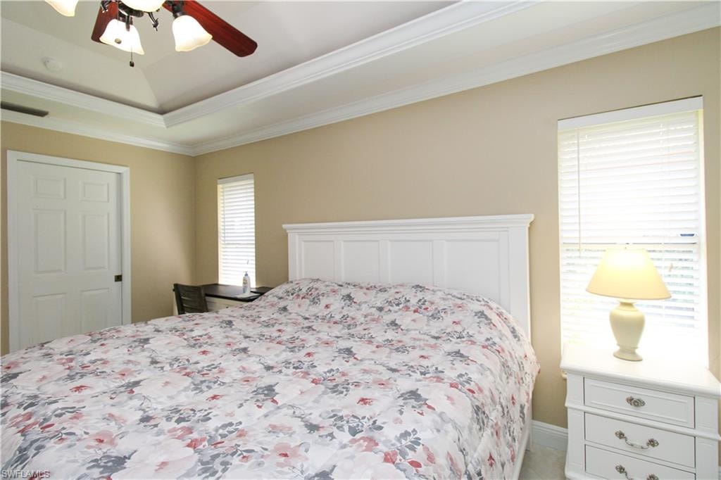 Bedroom featuring visible vents, a tray ceiling, ceiling fan, and ornamental molding