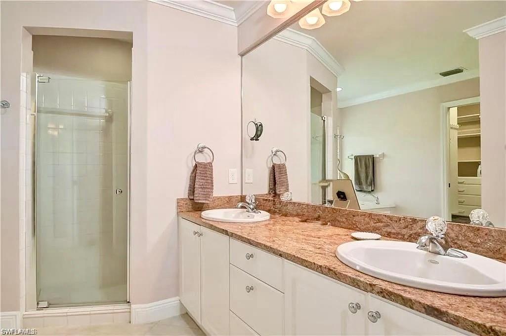 Full bath with a sink, a stall shower, and ornamental molding