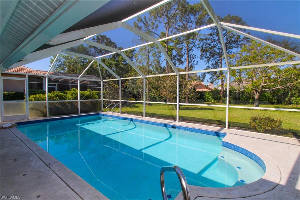 Outdoor pool featuring glass enclosure, a patio, and a lawn
