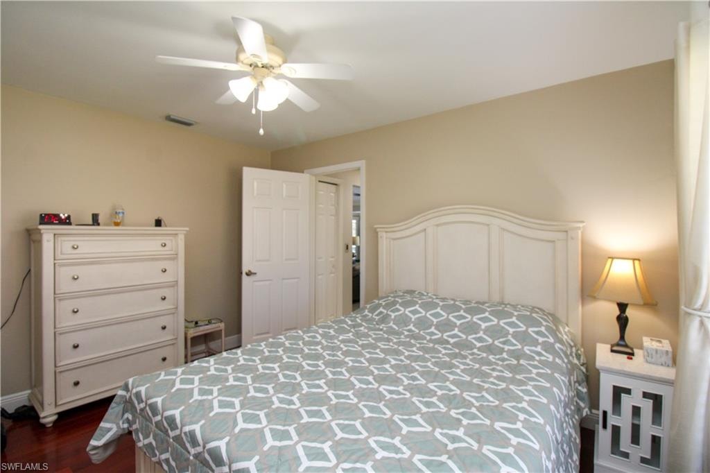 Bedroom with visible vents, dark wood-type flooring, and a ceiling fan