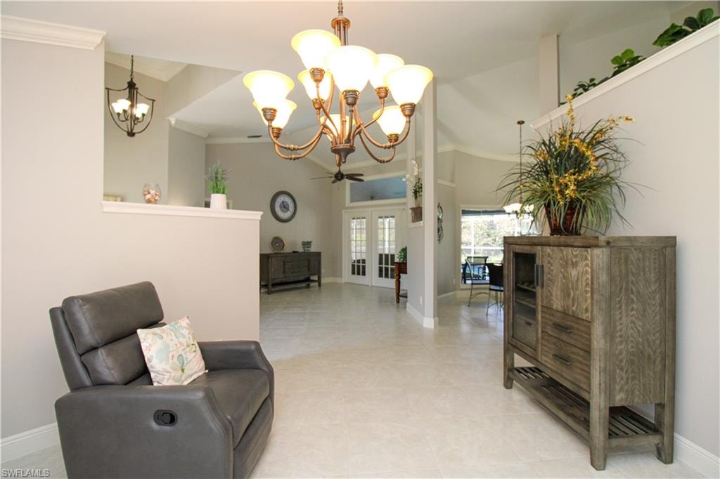 Sitting room with baseboards, ornamental molding, light tile patterned floors, french doors, and a notable chandelier