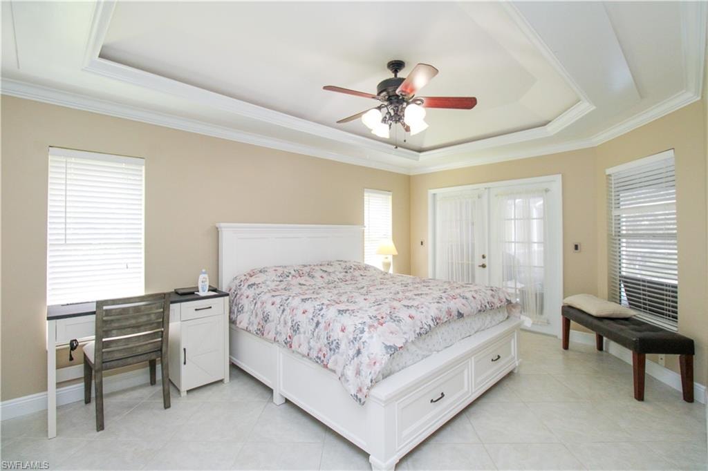 Bedroom with a raised ceiling, ceiling fan, and crown molding