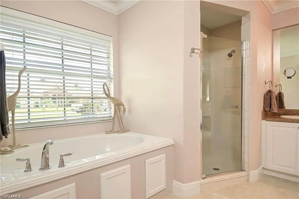 Full bath with a bath, a shower stall, vanity, and crown molding