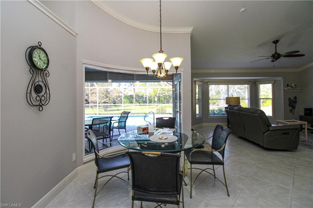 Dining area with light tile patterned floors, baseboards, a towering ceiling, crown molding, and ceiling fan with notable chandelier