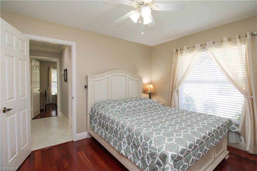 Bedroom with dark wood finished floors, baseboards, and ceiling fan