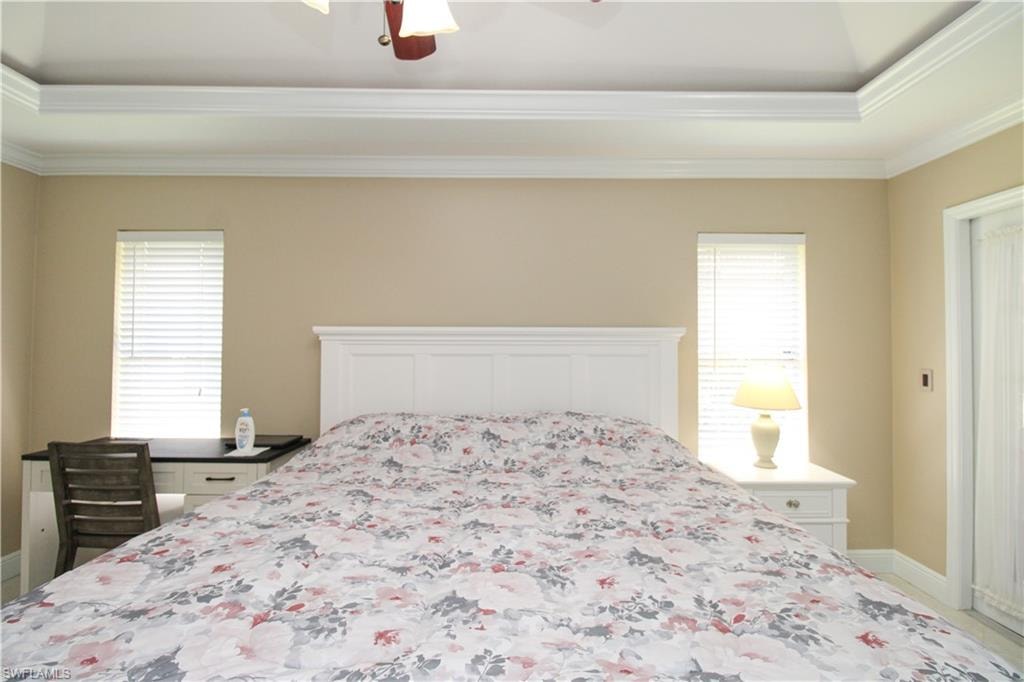 Bedroom featuring ceiling fan, baseboards, multiple windows, and ornamental molding