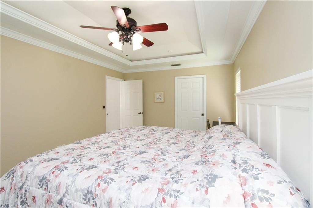 Bedroom featuring a raised ceiling, a ceiling fan, and ornamental molding