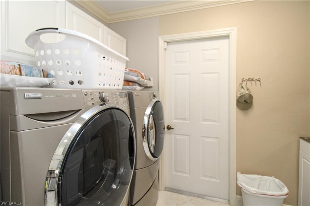 Washroom featuring crown molding, laundry area, and washer and clothes dryer