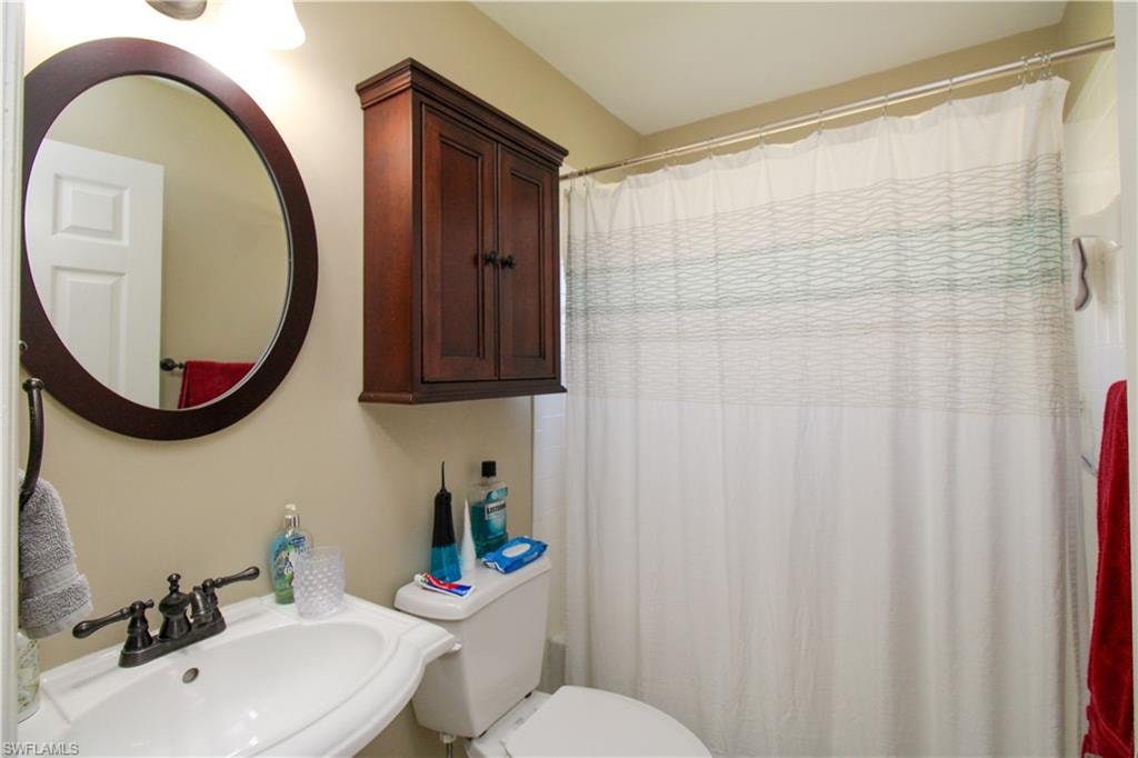 Bathroom featuring a sink, curtained shower, and toilet