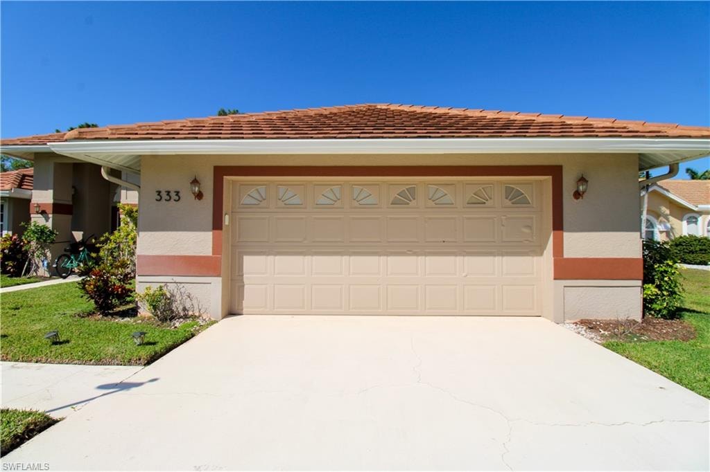 View of front of home with concrete driveway, an attached garage, a front yard, and stucco siding